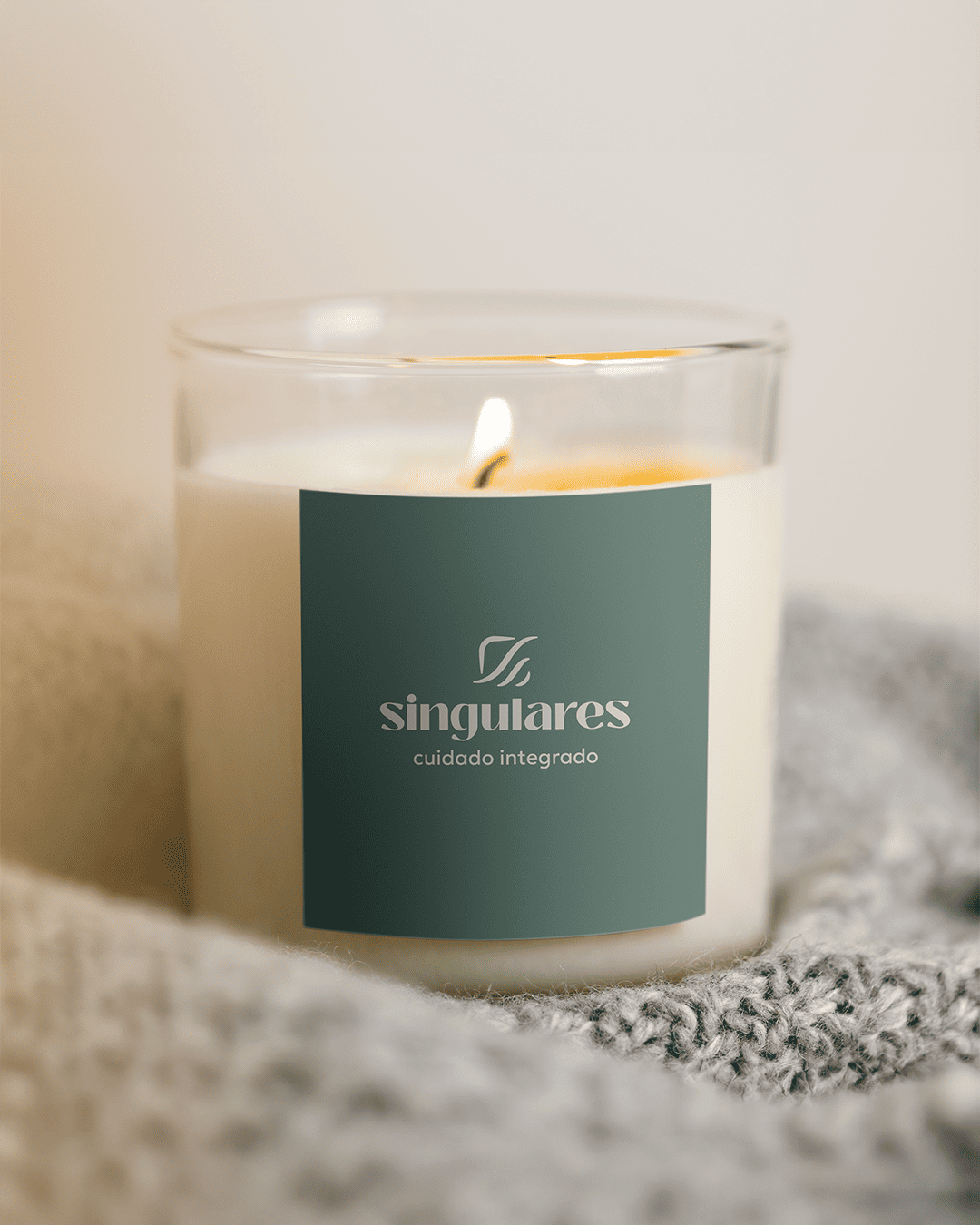 Candle with a green label and the Singulares Cuidado Integrado logo